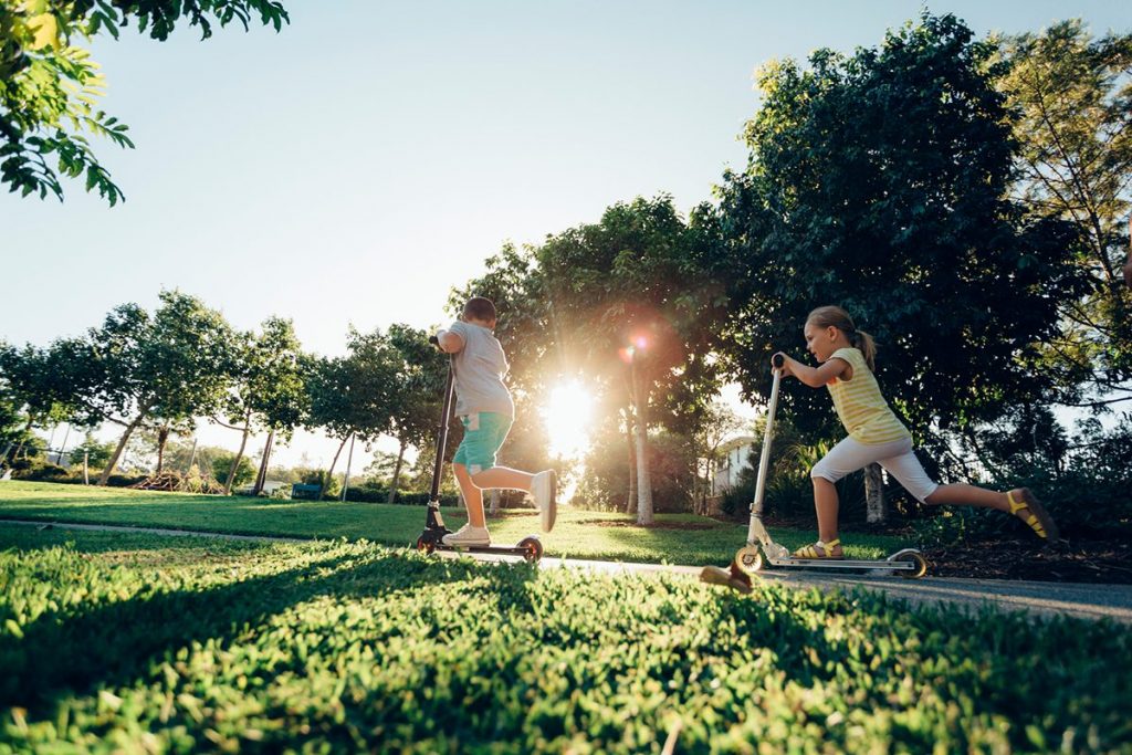 Children riding scooters in a park - Fiteni Homes